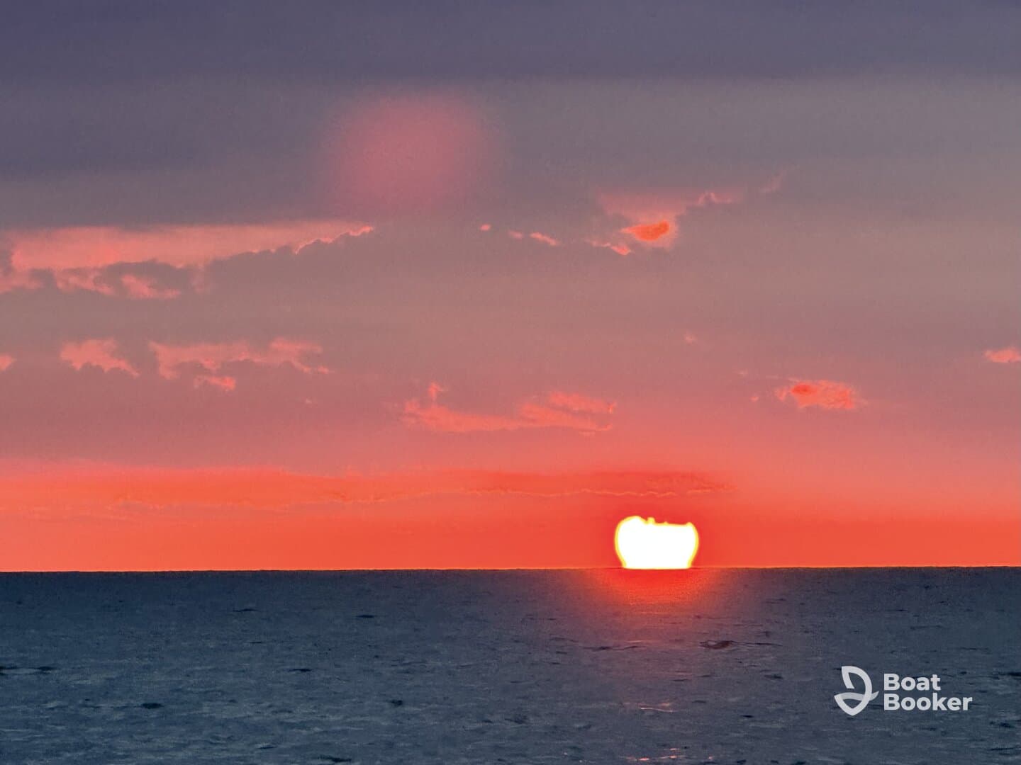 A stunning sunset over the ocean, showcasing vibrant colors as the sun dips below the horizon — a perfect backdrop for evening boat cruises.