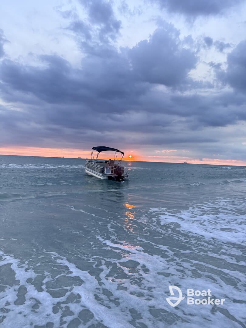 A serene sunset view of a pontoon boat gently resting in the shallow waters, creating a picturesque scene perfect for evening cruises.