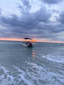 A serene sunset view of a pontoon boat gently resting in the shallow waters, creating a picturesque scene perfect for evening cruises.