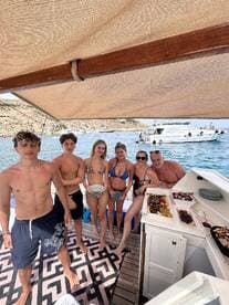A lively group enjoys a fun day on the boat, showcasing delicious food and a festive atmosphere — perfect for summer celebrations on the water.