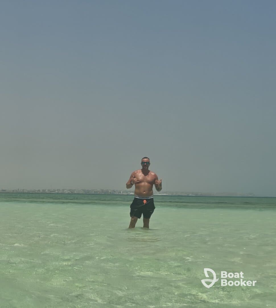 A man enjoys a refreshing swim in crystal-clear waters, showcasing the perfect beach day experience. Ideal for those seeking sun and fun on the water.