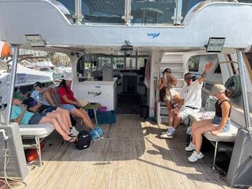 Guests relax inside the cabin of a boat, showcasing comfortable seating and a welcoming atmosphere for a day on the water.