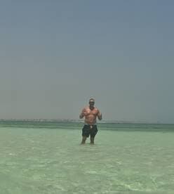 A man enjoys a refreshing swim in crystal-clear waters, showcasing the perfect beach day experience. Ideal for those seeking sun and fun on the water.