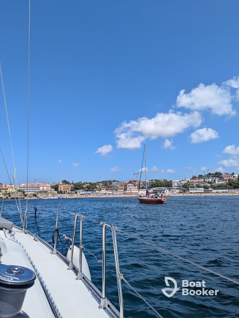 A scenic view of a yacht sailing along the coastline, showcasing beautiful waterfront properties and a clear blue sky — perfect for a day on the water.
