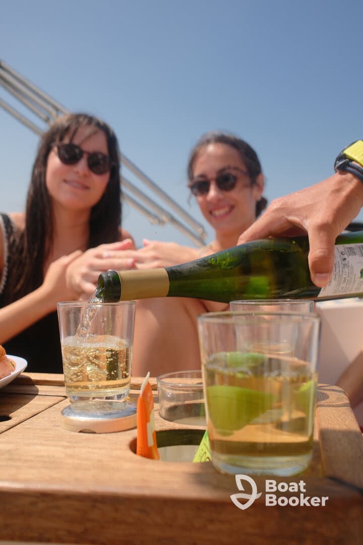 Two friends enjoy cocktails on a sunny boat, capturing the essence of a perfect day at sea — ideal for celebrations and social gatherings.