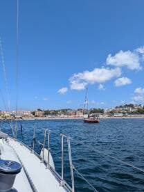 A scenic view of a yacht sailing along the coastline, showcasing beautiful waterfront properties and a clear blue sky — perfect for a day on the water.