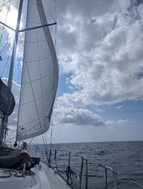 A beautiful view of a sailboat's sail catching the wind, showcasing the serene atmosphere of sailing on open waters.