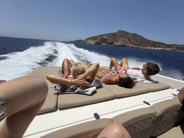A group enjoys a relaxing day on a boat, sunbathing and taking in the beautiful ocean views — perfect for summer outings and fun on the water.