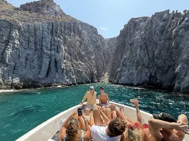 A lively group enjoys a scenic boat ride through stunning rock formations, capturing the essence of adventure and camaraderie on the water.