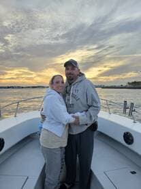 A couple embraces on the deck of a boat during a stunning sunset, capturing a romantic moment perfect for special occasions on the water.