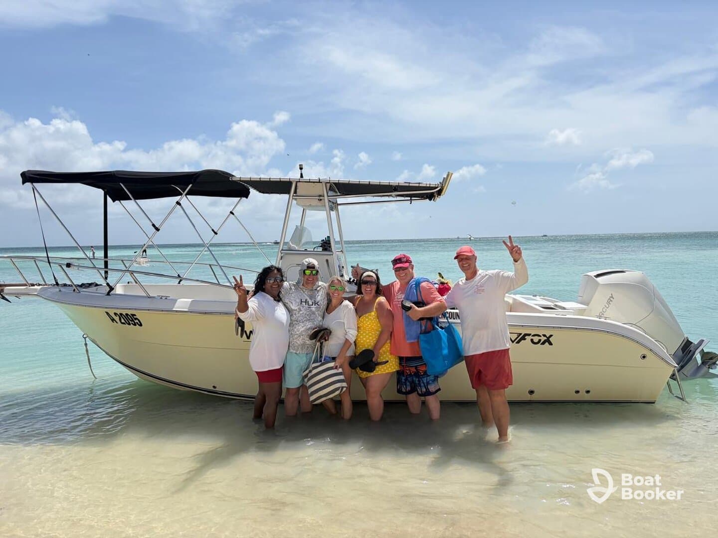 A cheerful group poses by their boat on a beautiful beach, capturing a moment of fun and celebration in the sun.