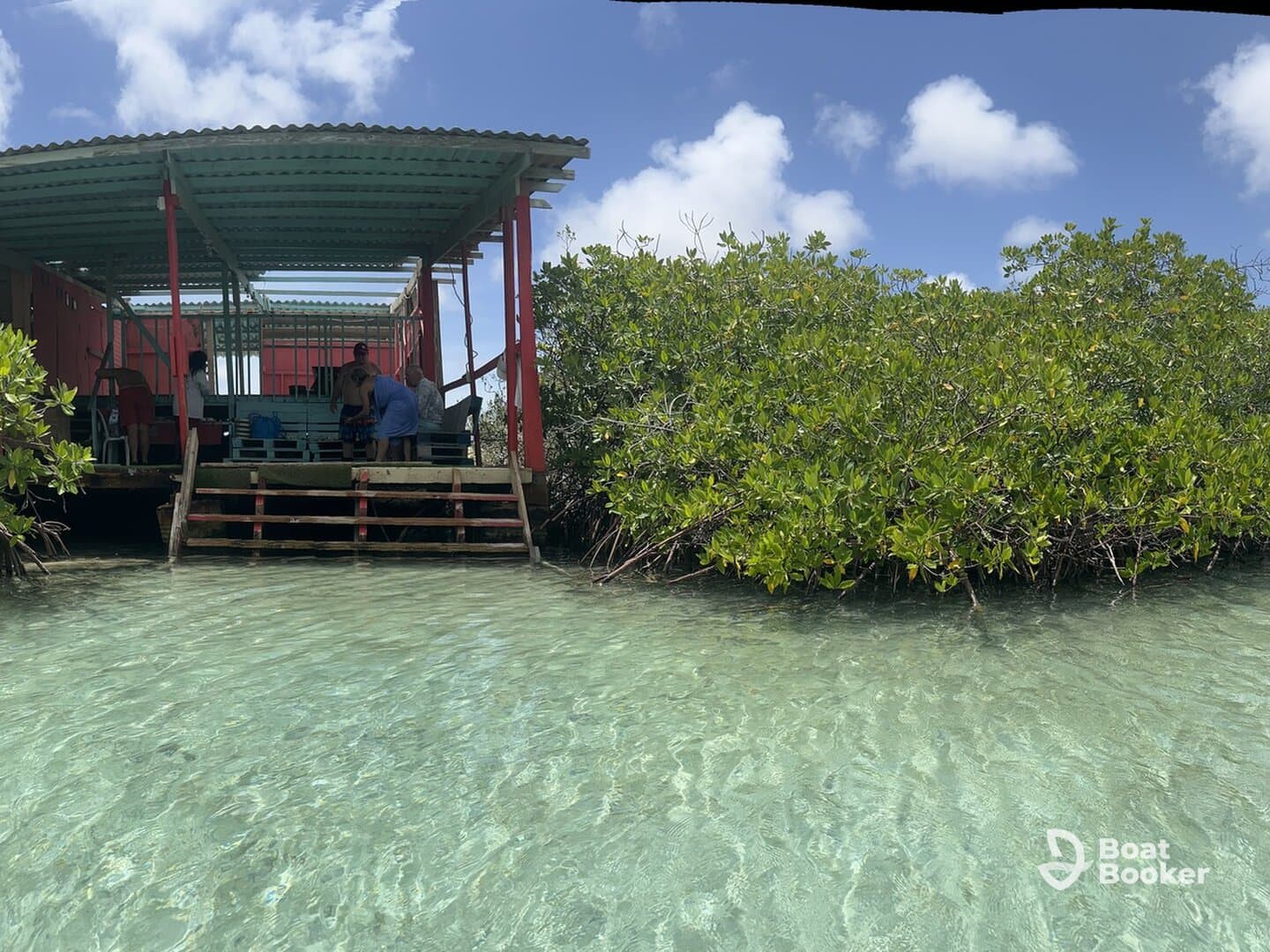 A group of people enjoys a sunny day at a waterfront location surrounded by mangroves, perfect for outdoor activities and relaxation.