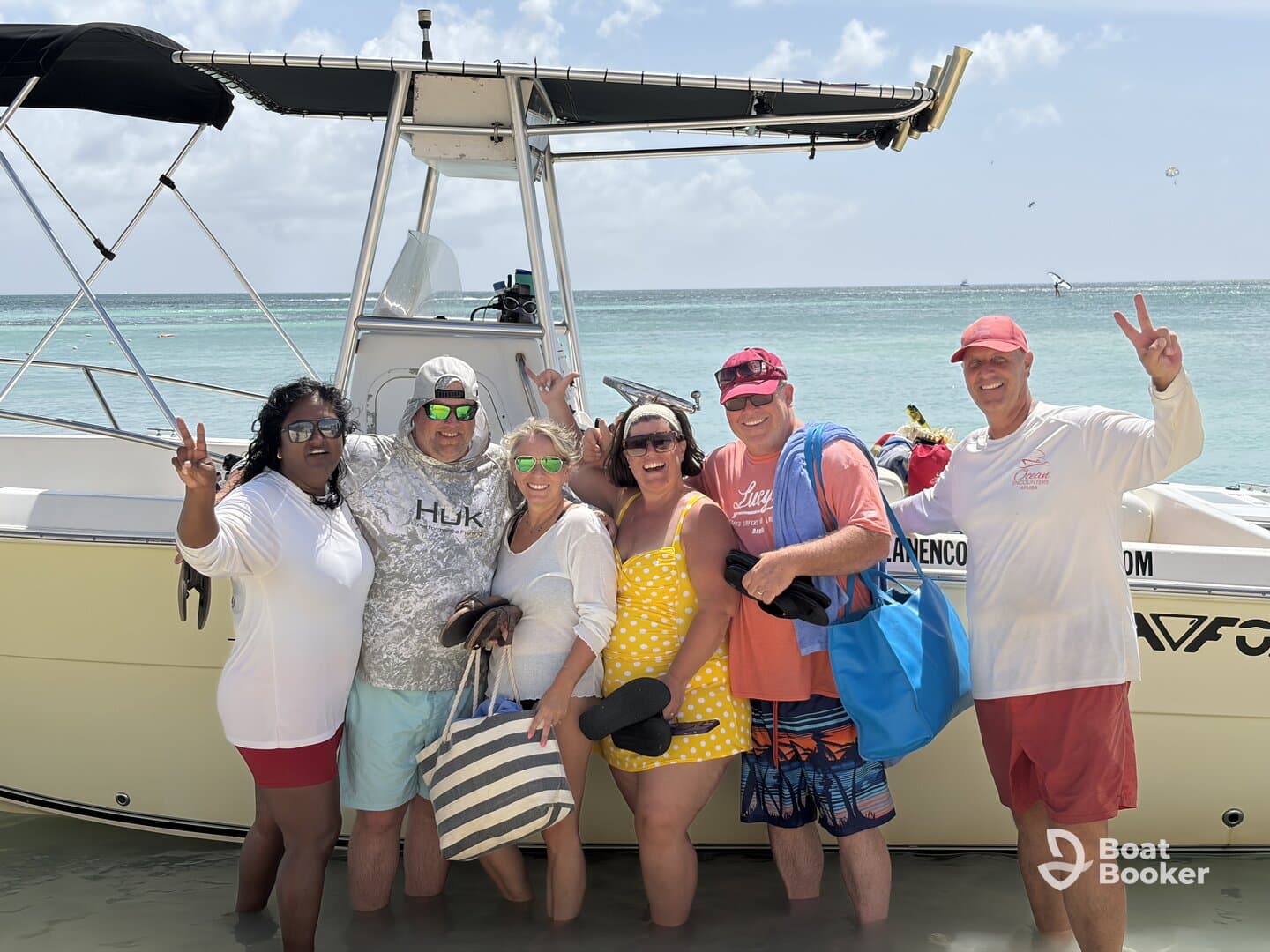 A cheerful group poses for a photo by their boat on the beach, capturing a fun day of sun and celebration on the water.