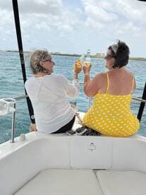 Two friends toast with cocktails while enjoying a sunny day on the boat, capturing the essence of friendship and celebration on the water.