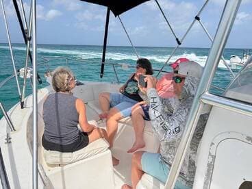 A group of friends relaxes on the deck of a boat, enjoying the ocean views and capturing memories on camera — perfect for a day out on the water.