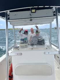 A cheerful group of friends enjoys a fun day on the water, celebrating aboard their boat with smiles and peace signs.