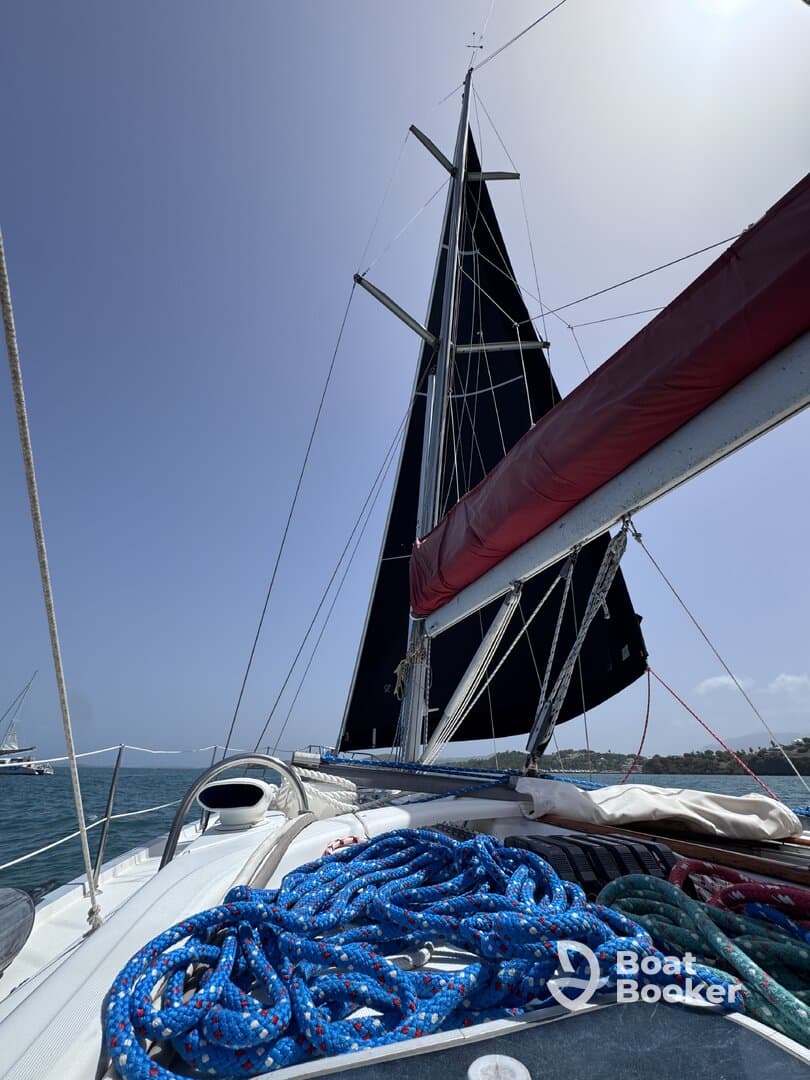 A close-up view of the helm area on a sailboat, showcasing colorful ropes and the impressive black sail against a clear blue sky — perfect for sailing enthusiasts.