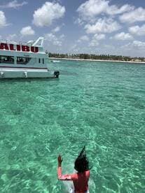 A person enjoys swimming in the crystal-clear waters near a Malibu boat, capturing the essence of a perfect day on the water.