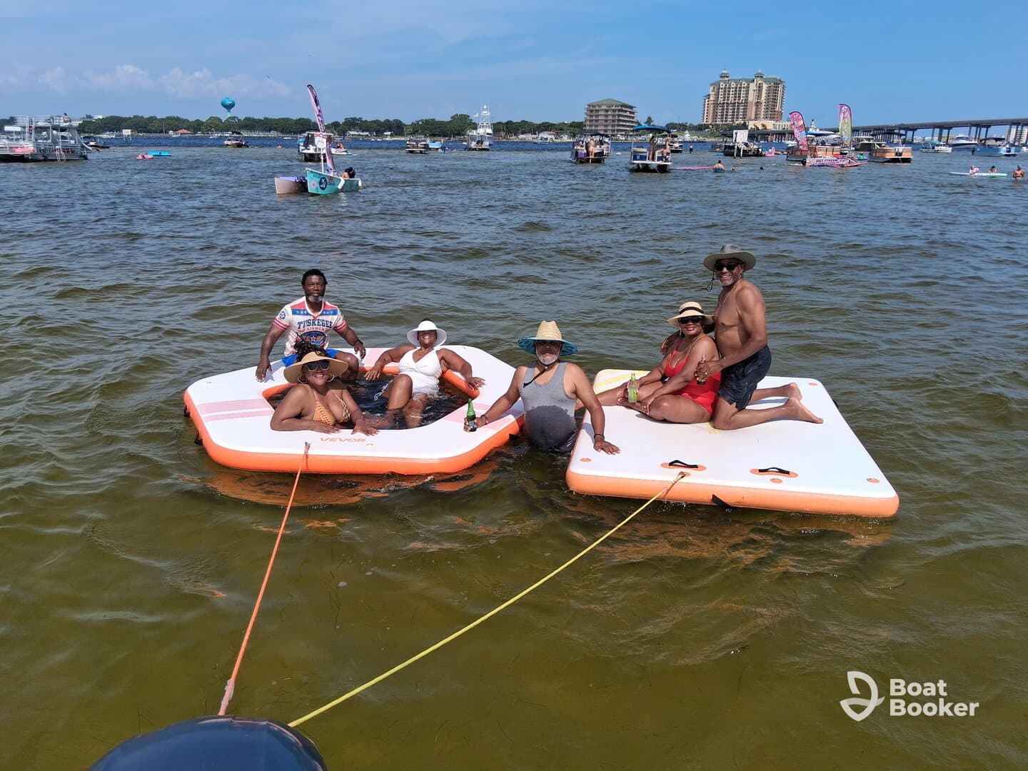 A lively group enjoys a day on the water, relaxing on floating mats while soaking up the sun — perfect for summer fun and social gatherings.