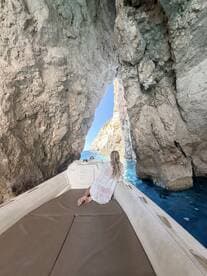 A serene moment as a woman relaxes on the boat, framed by stunning rock formations and crystal-clear waters — a perfect escape into nature.