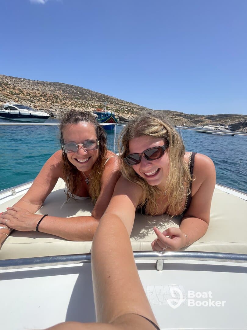 Two friends enjoy a sunny day on a boat, smiling and relaxing as they soak up the sun — a perfect moment for summer adventures on the water.