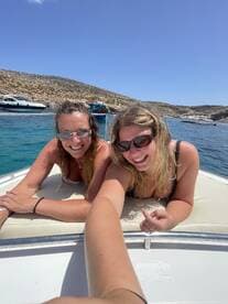 Two friends enjoy a sunny day on a boat, smiling and relaxing as they soak up the sun — a perfect moment for summer adventures on the water.