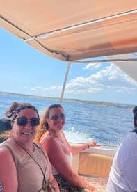 Two women enjoy a sunny boat ride, smiling and taking in the ocean views — a perfect moment of fun and relaxation on the water.