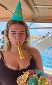A woman celebrates her birthday on a boat, wearing a festive hat and surrounded by party decorations — a perfect moment for joyful celebrations on the water.