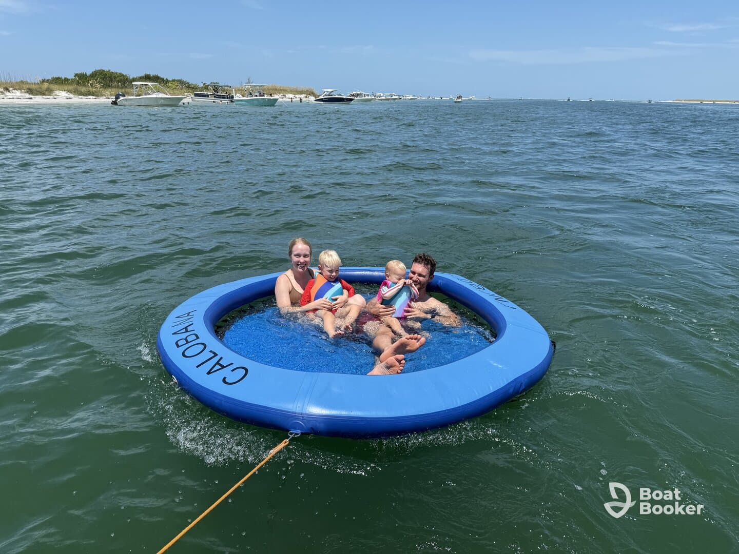 A joyful family enjoys a sunny day on a floating mat in the water, creating lasting memories of fun and laughter at the beach.