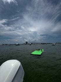A fun day on the water with friends enjoying a floating mat, surrounded by boats and a beautiful sky — perfect for summer adventures.