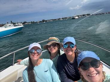 A cheerful group of friends poses for a selfie on a boat, enjoying a sunny day on the water — perfect for creating lasting memories together.
