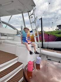 A young girl in a colorful life jacket enjoys her time on the boat, highlighting safety and fun on the water. Perfect for family boating adventures.