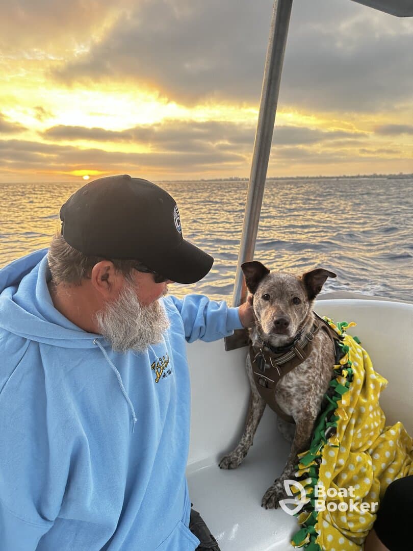 A man enjoys a serene sunset on a boat with his dog, showcasing the perfect companionship for a relaxing day on the water.