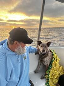 A man enjoys a serene sunset on a boat with his dog, showcasing the perfect companionship for a relaxing day on the water.