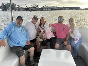 A cheerful group of friends enjoys a relaxing moment on a boat, accompanied by a dog, showcasing the joy of shared experiences on the water.