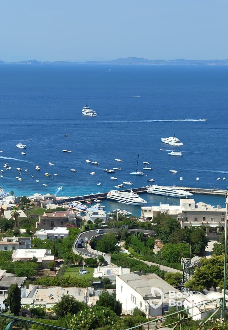 A stunning aerial view of a bustling harbor filled with various boats and yachts, showcasing the beautiful coastline and vibrant blue waters.