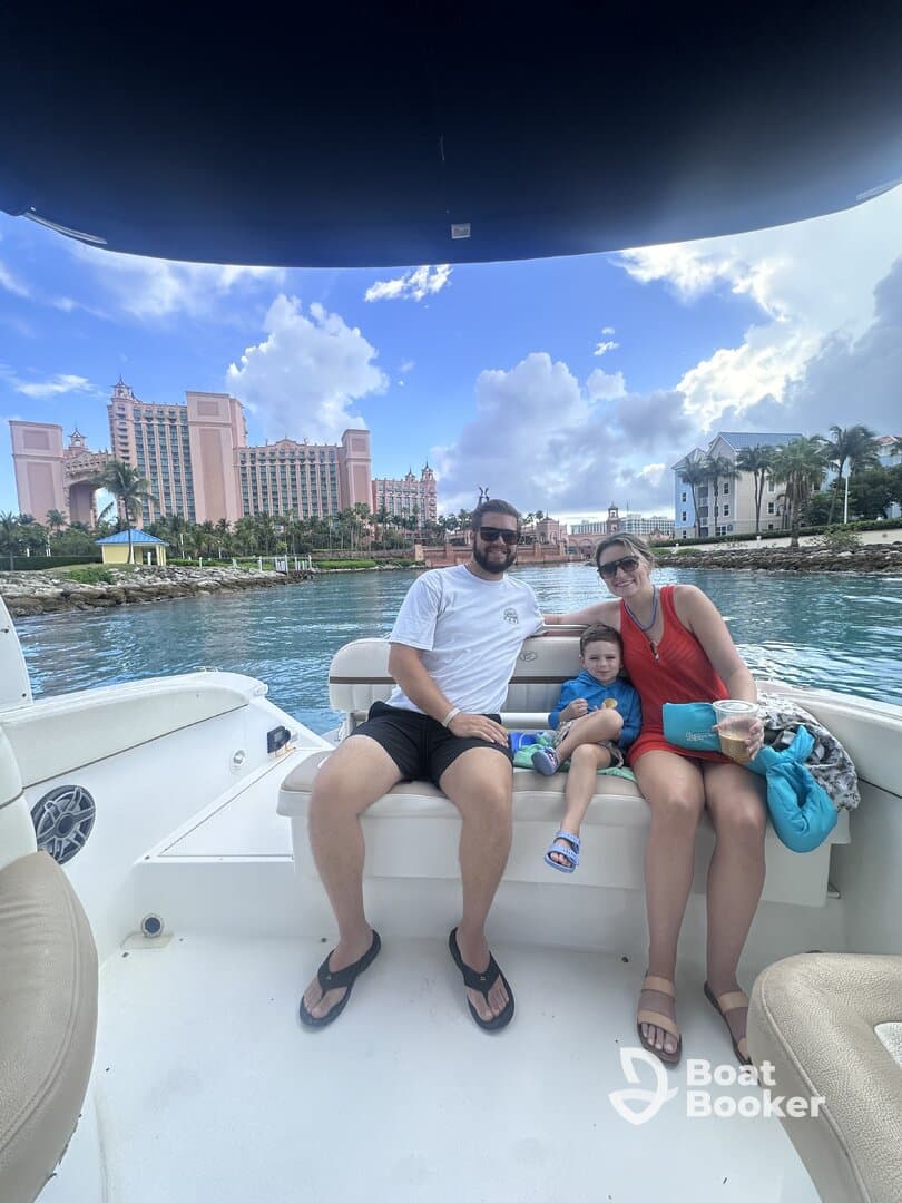A family enjoys a relaxing moment on a boat with the iconic Atlantis resort in the background, capturing the essence of a perfect vacation on the water.