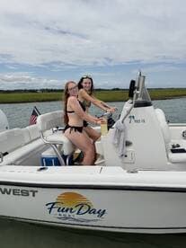 Two friends enjoy a sunny day on the water, taking the helm of a Fun Day boat — perfect for summer adventures and memorable outings.