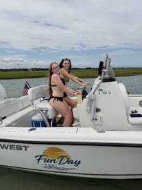 Two friends enjoy a sunny day on the water, taking turns at the helm of their Fun Day boat — perfect for summer adventures and creating lasting memories.