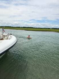 A person enjoys a refreshing swim in clear waters next to a boat, showcasing the perfect summer day on the water.