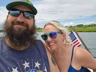 A cheerful couple poses for a selfie on a boat, enjoying a sunny day on the water — perfect for capturing memorable moments during their adventure.