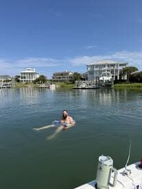 A man enjoys a relaxing swim in calm waters, showcasing the perfect summer day by the waterfront.