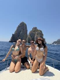 A group of friends enjoys a sunny day on a boat near the iconic rock formations of Cabo San Lucas, showcasing a perfect blend of fun and relaxation on the water.