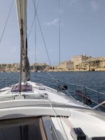 A stunning view from the deck of a sailboat, showcasing the vessel's structure as it navigates near a historic coastal fortification.
