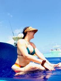 A woman enjoys a sunny day on the water, relaxing and playing in the blue waves — a perfect moment for fun and relaxation on a boat trip.