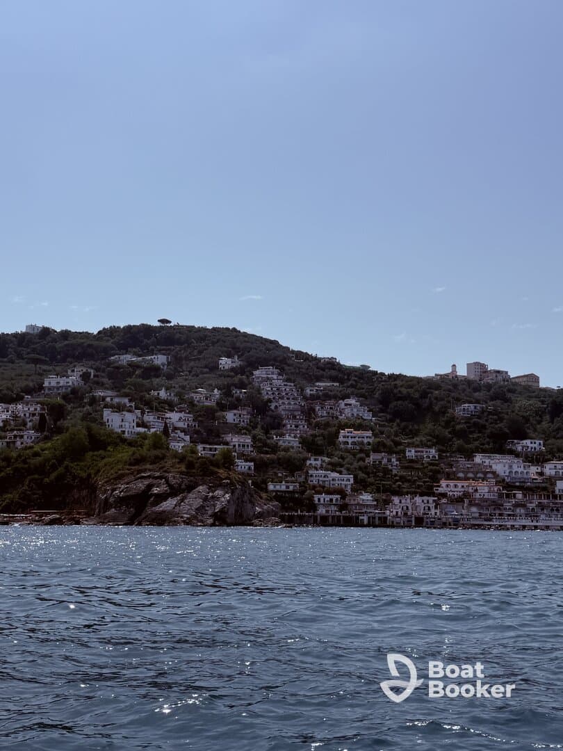 A picturesque view of a coastal town nestled on a hillside, showcasing beautiful architecture against a serene water backdrop — perfect for exploring scenic destinations by boat.
