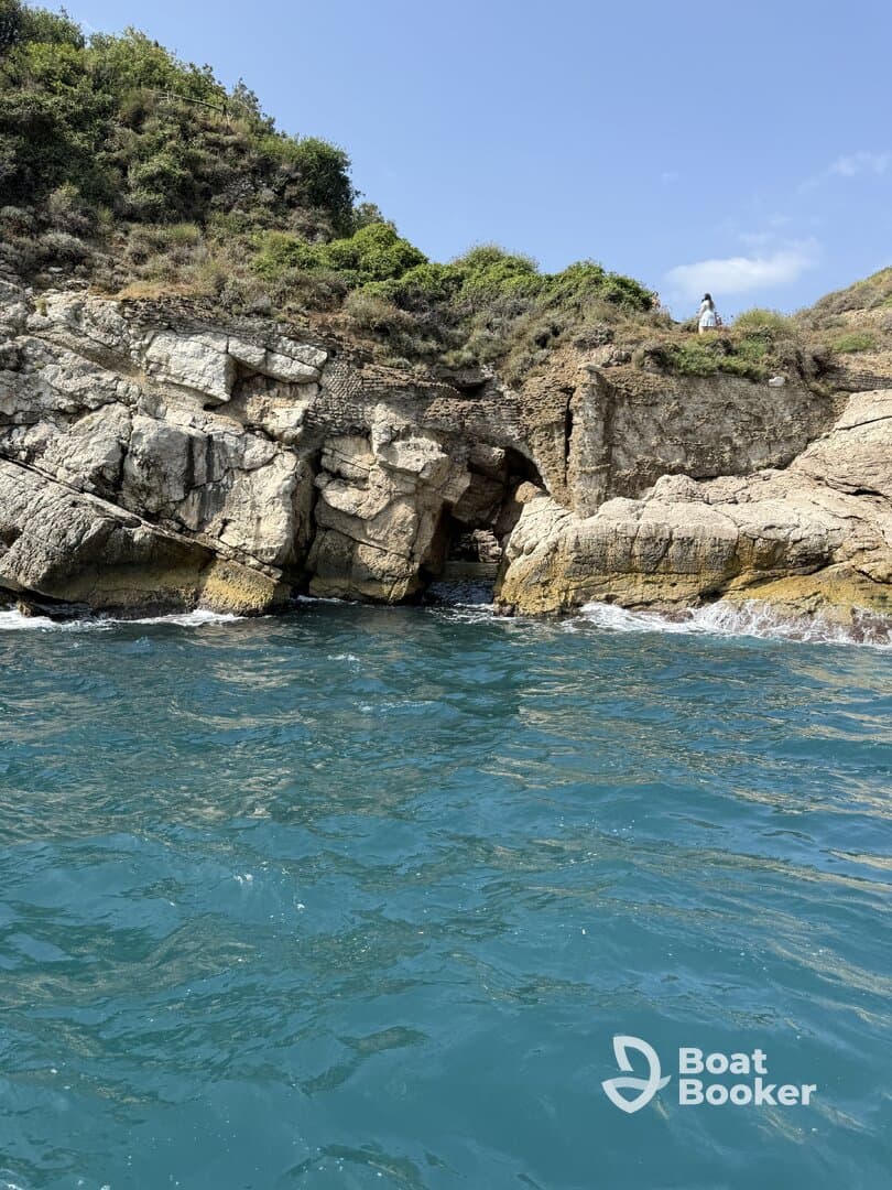 A scenic view of a rocky coastline with lush greenery, featuring a person exploring the area — a perfect backdrop for coastal adventures.