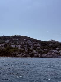 A picturesque view of a coastal town nestled on a hillside, showcasing beautiful architecture against a serene water backdrop — perfect for exploring scenic destinations by boat.