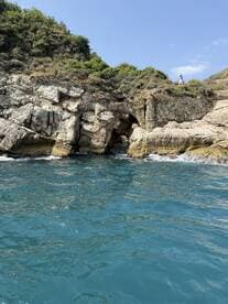 A scenic view of a rocky coastline with lush greenery, featuring a person exploring the area — a perfect backdrop for coastal adventures.