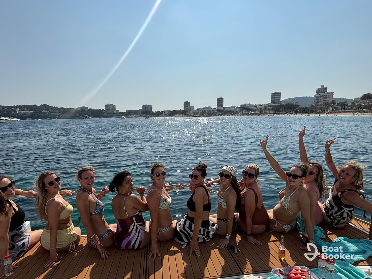 A lively group of friends enjoys a sunny day on a yacht, celebrating with smiles and fun by the water — perfect for a beach party or girls' getaway.
